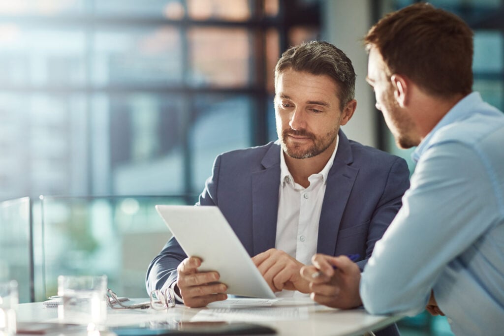 Two men discussing a digital assessment at Clarity Psychology in a professional office setting.